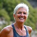Sarah J., a vibrant woman in her late 50s, smiling confidently while hiking a mountain trail